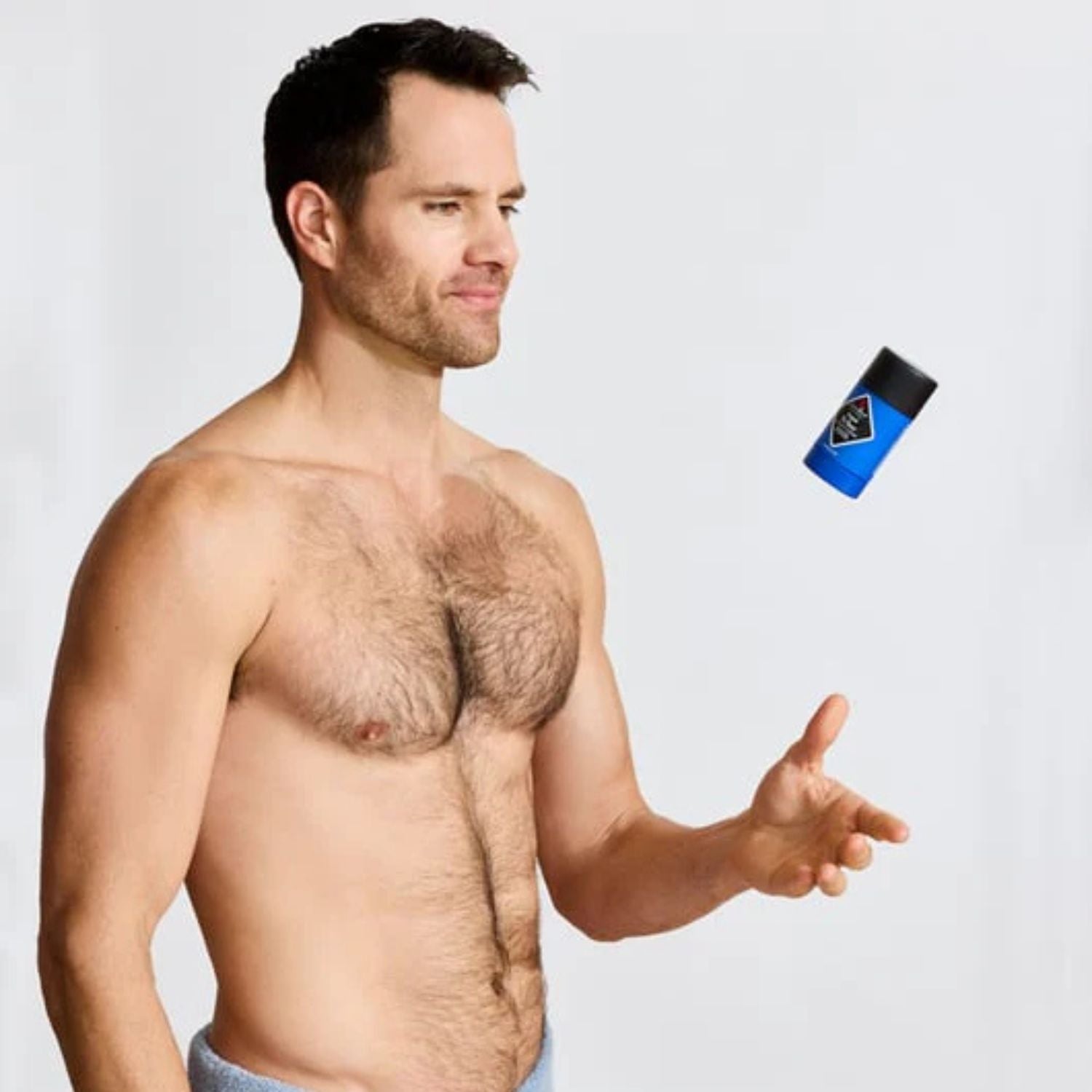 Man pointing to a deodorant stick on a light gray background
