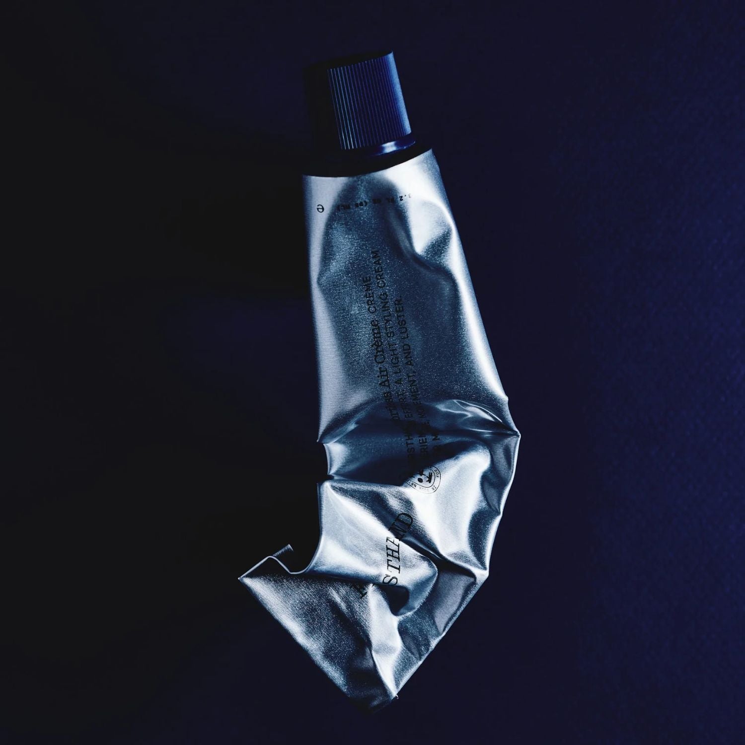 Silver tube with blue cap on a black background