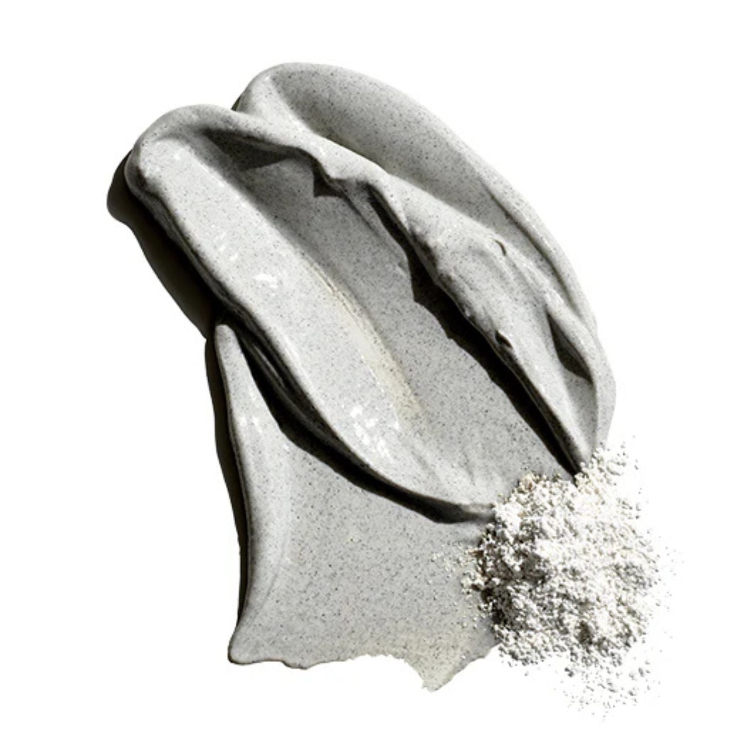 Gray clay cleanser with sand spilling out on a white background