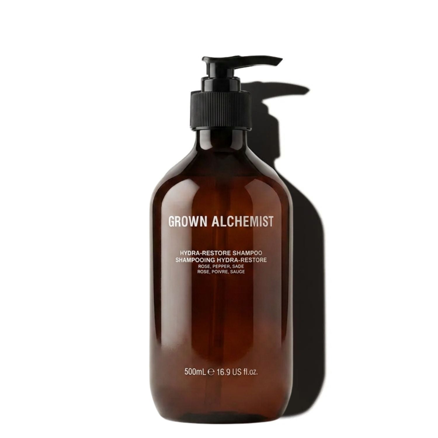 A 500mL amber brown pump bottle of Grown Alchemist Hydra-Restore Shampoo, shown on a white background with a prominent cast shadow.