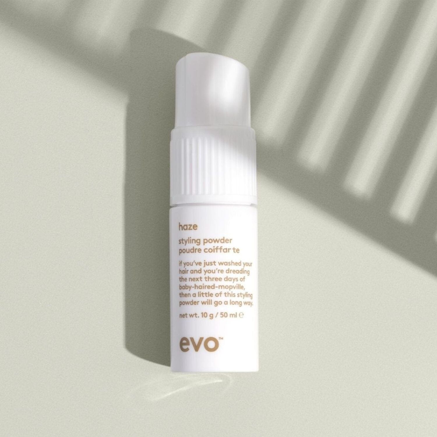 Evo Haze Styling Powder on a light green background with shadows