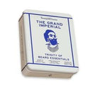 A square metal tin of Beard Essentials by The Grand Imperial, featuring a white label with blue text and a blue illustrated beard logo, shown on a plain white background.