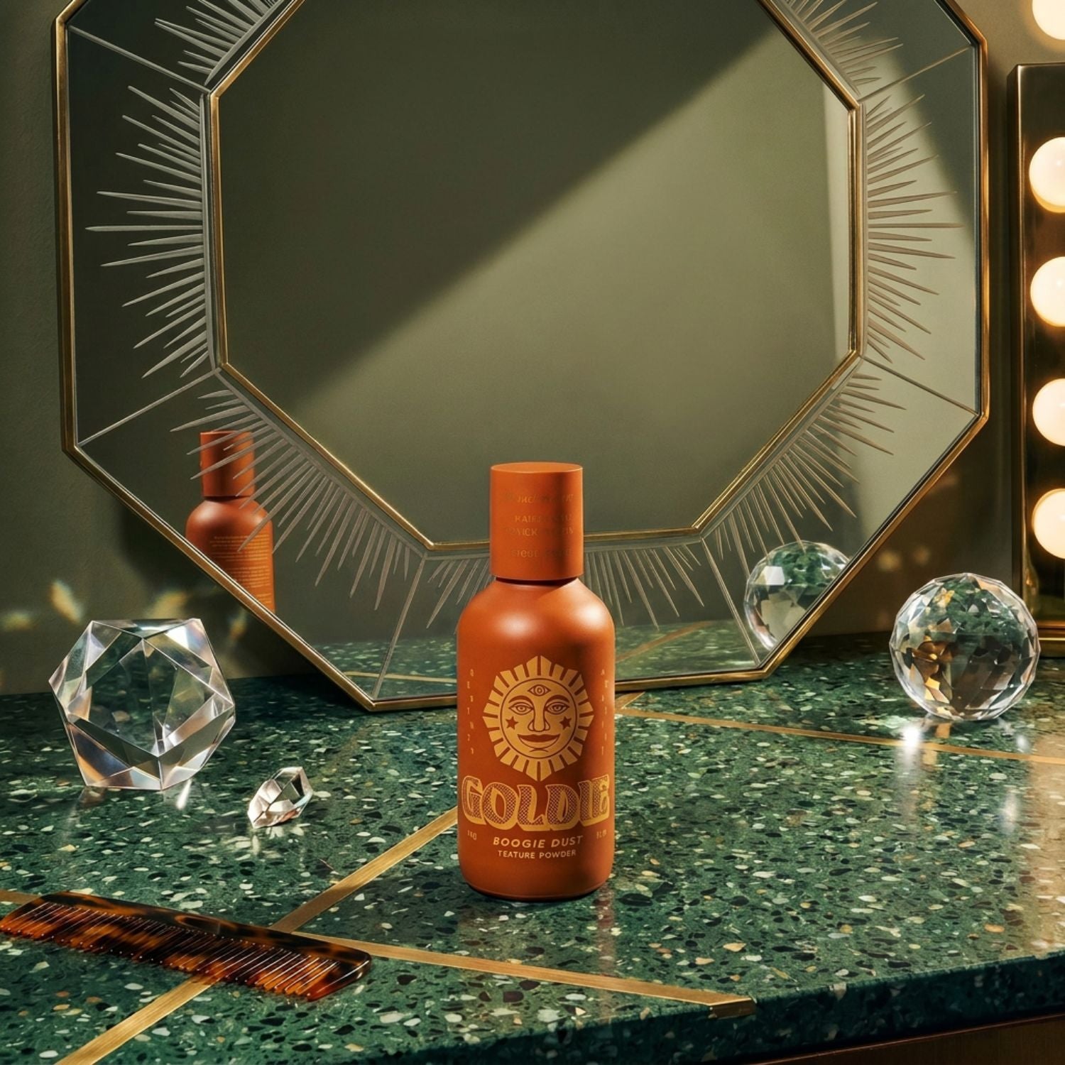 Bottle of Boogie Dust Hair Powder on a retro 70s countertop with a mirror in  the background and reflective crystals on the counter as well