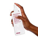 A hand holding a white spray bottle of EVO baby got bounc against a plain white background.
