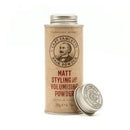 A vintage-style metal tin of Matt Styling Volumizing Powder, shown in a warm beige/tan color with a silver lid, alongside a separate silver lid on a white background.