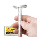 Hand holding a safety razor with a pack of feather blades with yellow packaging in the background