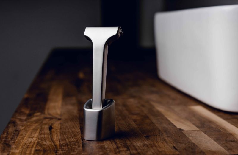 Metallic razor tool on a wooden surface with a blurred background