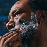 Man shaving with a razor, close-up of face with blurred background